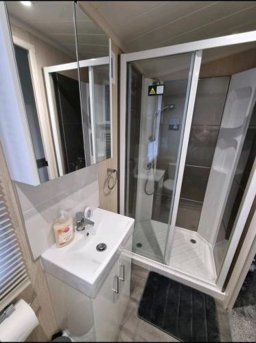 a white bathroom with a shower and a sink at Seven Sunsets, Padstow in Padstow