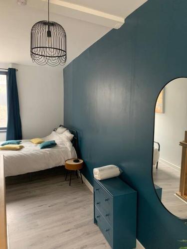 - une chambre dotée d'un mur bleu avec un lit et un miroir dans l'établissement Maison centre-ville Cambrai, à Cambrai