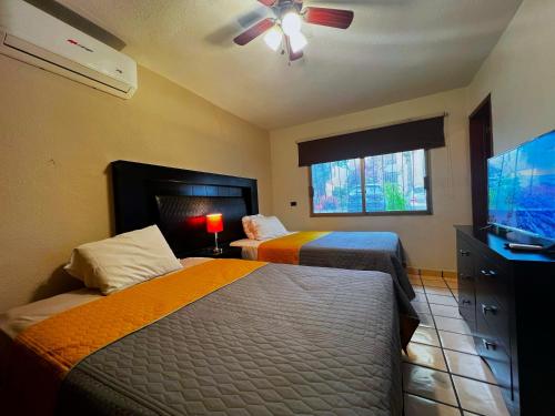 a bedroom with two beds and a flat screen tv at Casa Revolucion: 2BR/2Ba Casita close to downtown with private parking in Cabo San Lucas