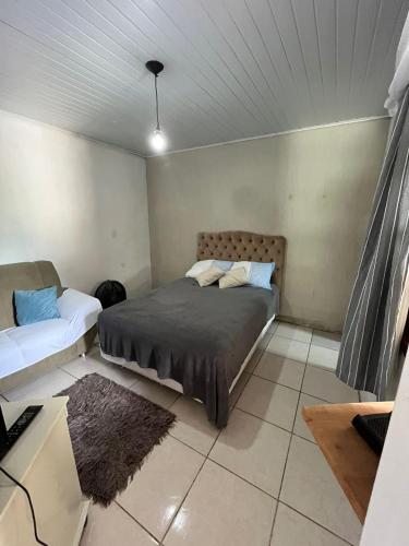 um quarto com uma cama e um sofá em Casa com suíte em Blumenau