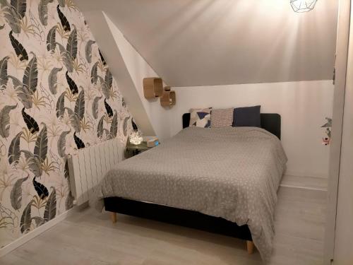 1 dormitorio con cama y pared en Chez Nadège et Nicolas, en Aubergenville