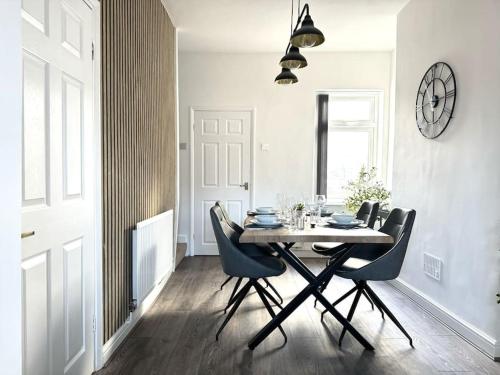 a dining room table with chairs and a clock on the wall at Stylish home in York - Free Wifi & Parking - Close to Racecourse & City Centre in York