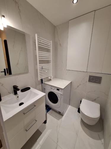 La salle de bains blanche est pourvue d'un lavabo et d'un lave-linge. dans l'établissement Appartement comme une suite d’hôtel, à Cannes