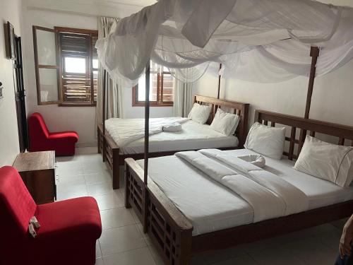 a bedroom with two beds and a red chair at Bin Omar Malindi Apartment in Stone Town