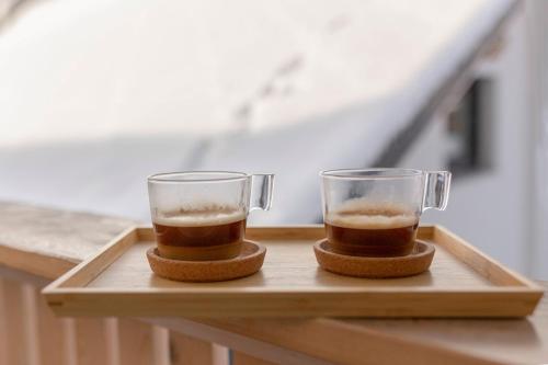 two glasses of coffee sitting on a wooden tray at Deluxe Apartments 55 in Kranjska Gora