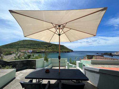 a table with an umbrella on a balcony at Mar Rosa - Terraço Vista Praia in Horta