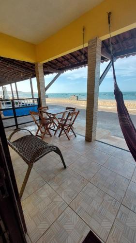 um alpendre com cadeiras e uma rede de descanso e a praia em Chalés Canto do Mar em Redonda