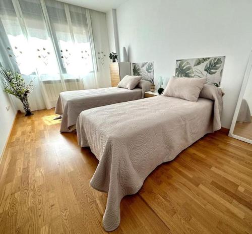 two beds in a room with wood floors at Studio 14 + garaje incluido. Nuevo, elegante, acogedor. in Haro