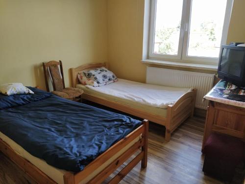 a small room with two beds and a television at Pokoje Goscinne Buzuki in Ciechanów