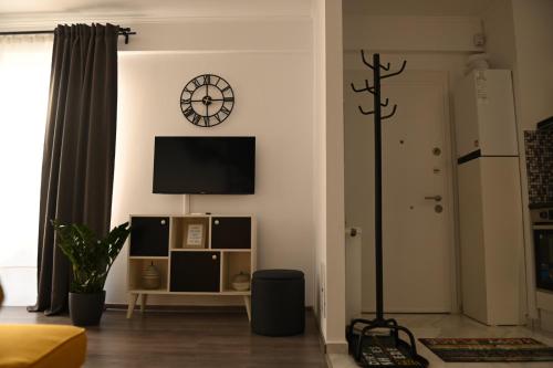 a living room with a tv and a clock on the wall at Mathias Airport Residences & Therme-Self Check-in in Otopeni
