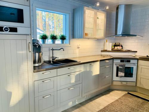 a kitchen with white cabinets and a sink at Vuolenkosken Helmi - laadukas ympärivuotinen kohde in Huutotöyry