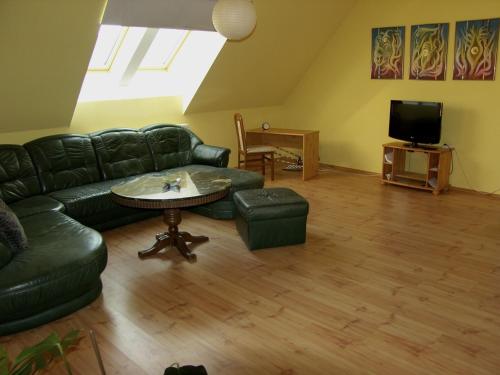 a living room with a black leather couch and a table at Hunyadi Apartment in Kalocsa