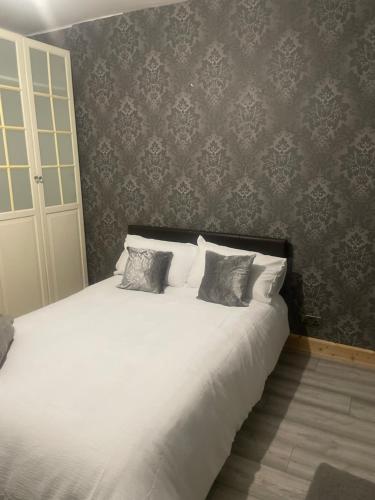 a bedroom with a white bed with two pillows at Home from Home in Merton
