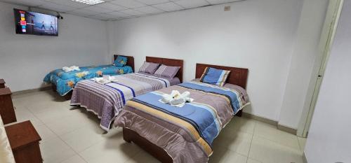 2 camas en una habitación con TV en la pared en HOTEL TICLIO, en Cajamarca