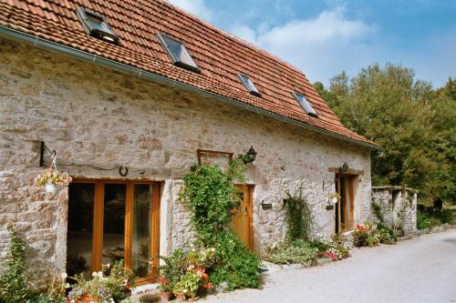 an old stone house with a red roof at Les gites et chambres d'hôtes du Mas de bouzou in Grèzes