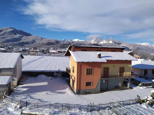 uma casa coberta de neve com montanhas ao fundo em Affittacamere La CRICOVA di Iulia em Santo Stefano