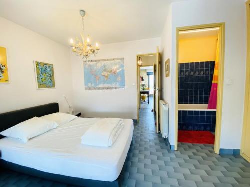 - une chambre avec un lit blanc et un lustre dans l'établissement Les Grenadines - Duplex vue mer avec parking en sous sol MAE-2014, à La Grande Motte