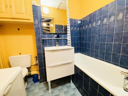 La salle de bains est pourvue de carrelage bleu, d'un lavabo et de toilettes. dans l'établissement Les Grenadines - Duplex vue mer avec parking en sous sol MAE-2014, à La Grande Motte