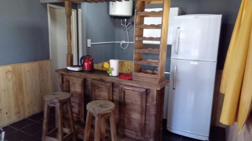 a kitchen with a counter and a refrigerator and stools at Cabañas EL SOLEADO in Zonda