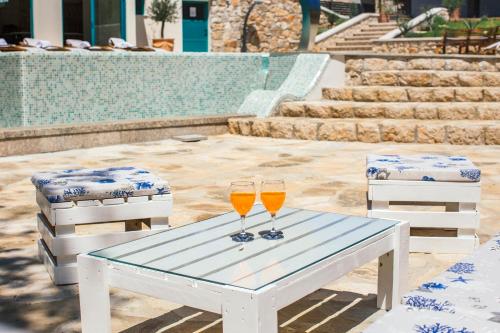 two wine glasses on a table next to a pool at VILLA G., Relaxing and Unique nest of Enjoyment in Imotski