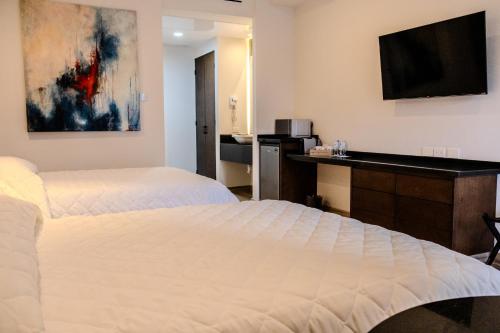 Cette chambre comprend deux lits et un bureau. dans l'établissement Hotel Gran Avenida, Navojoa, à Navojoa
