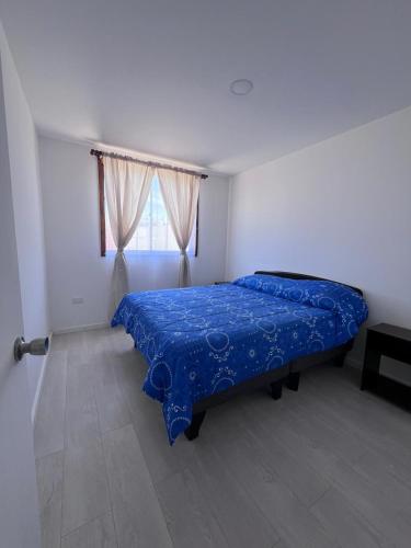 a bedroom with a bed with a blue blanket on it at Casa Playa Loreto in Caldera
