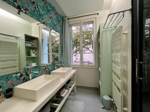 une salle de bain avec deux lavabos et un grand miroir dans l'établissement Maison Marais - calme et terrasse, à Paris