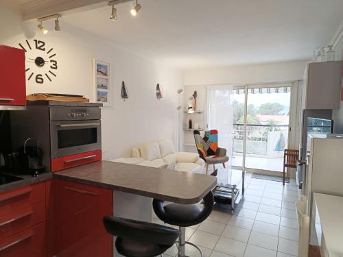 une cuisine avec des placards rouges et un comptoir avec des chaises dans l'établissement Baie d'Azur, à Saint-Raphaël