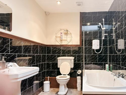 a bathroom with a toilet and a sink and a tub at 4-bed penthouse - Old Converted Church - FREE Parking in Pontypool