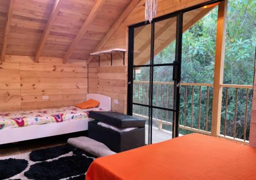Cette chambre comprend un lit et une grande fenêtre. dans l'établissement Cabaña con Jacuzzi privado/BBQ y Chimenea ecológica, à Guarne