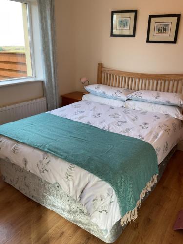 a bedroom with a bed with a green and white comforter at The Getaway, Miltown Malbay in Miltown Malbay