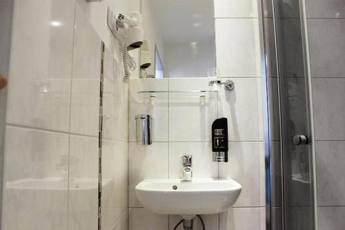 a white bathroom with a sink and a shower at Skyline Hotel Hannover in Hannover