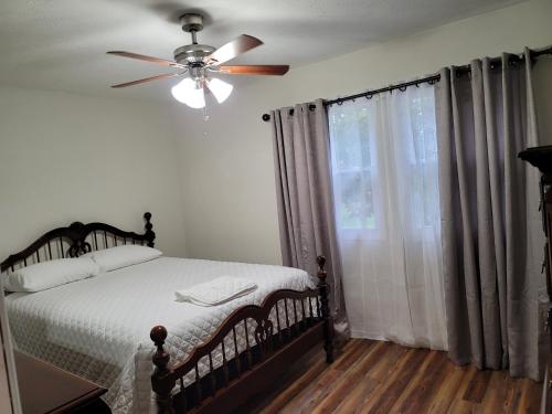 a bedroom with a bed with a ceiling fan and a window at Tranquil Retreat in the heart of Bethany 