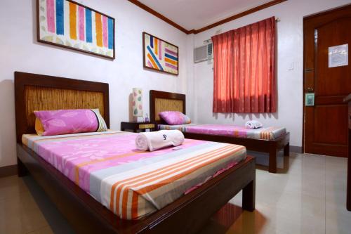 a bedroom with two beds and a window at Papierus Pensionne in Kalibo