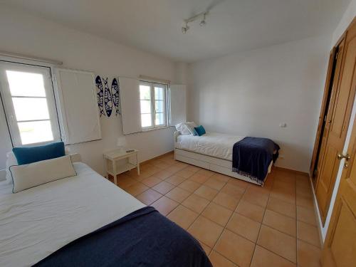 een slaapkamer met 2 bedden en 2 ramen bij Casa Água & Sal in Castro Marim