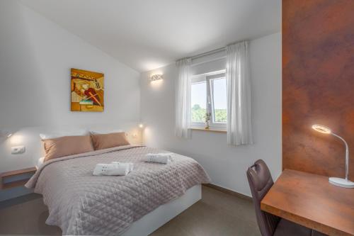 a bedroom with a bed and a table and a window at Villa Opal in Tar