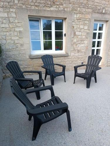 three black chairs sitting in front of a building at Gîte à Travers champs in Colombières