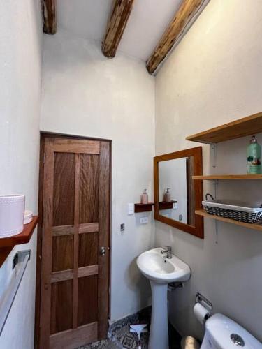 a bathroom with a sink and a wooden door at Bungalow Lamay - Cusco in Lamay