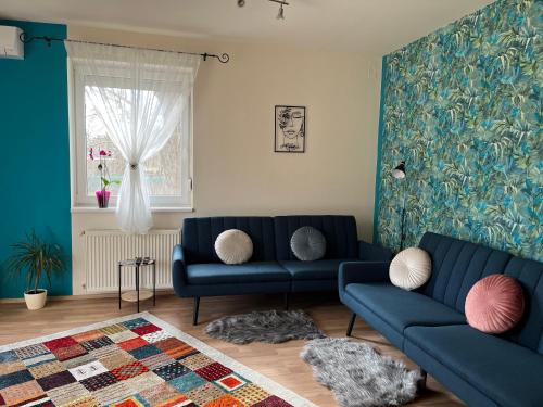 a living room with two blue couches and a window at Király Családi Apartman- Royal Family Apartment in Budapest