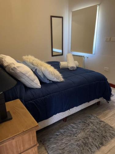 a bedroom with a blue bed with pillows and a mirror at Tandil del Lago in Tandil