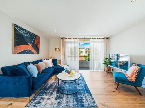 a living room with a blue couch and a table at XQ Collection Saltwater Bondi Beach in Sydney