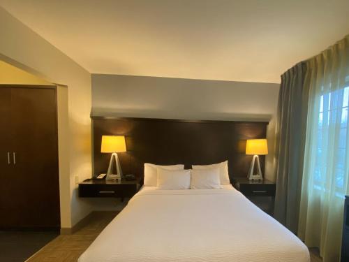 a bedroom with a large white bed with two lamps at Staybridge Suites Syracuse Liverpool by IHG in Liverpool