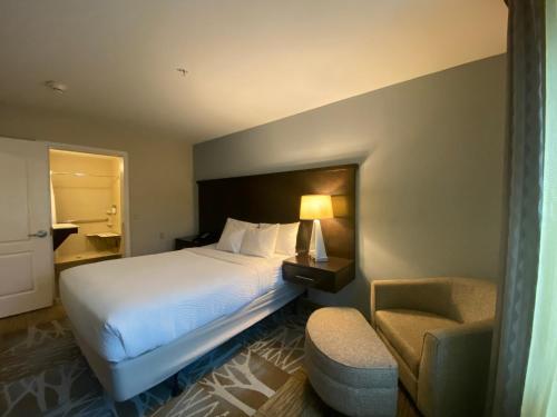 a hotel room with a bed and a chair at Staybridge Suites Syracuse Liverpool by IHG in Liverpool