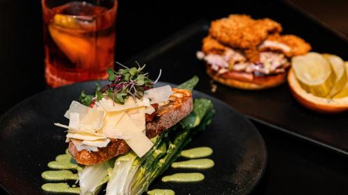 a sandwich with cheese and vegetables on a black plate at Kimpton Hotel Palomar Los Angeles Beverly Hills by IHG in Los Angeles
