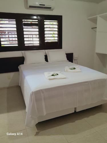 1 dormitorio con 1 cama blanca y 2 toallas en Caçadores de Aventuras Flats, en Pipa