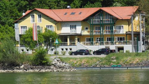 ein großes Gebäude mit Autos vor dem Wasser in der Unterkunft Gasthof-Pension Luger in Wesenufer