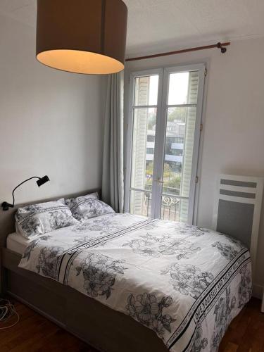 a bedroom with a bed and a large window at chambre d'hote in Issy-les-Moulineaux