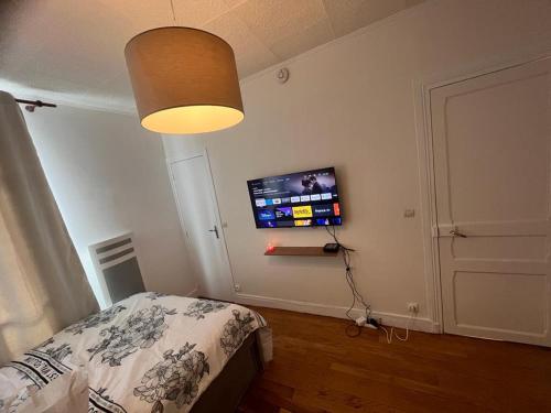 a bedroom with a bed and a tv on the wall at chambre d'hote in Issy-les-Moulineaux