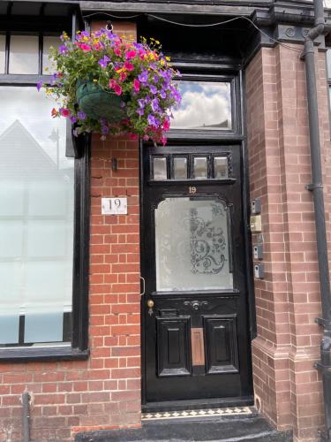 a black door with flowers on the side of a brick building at Deluxe Three Bed BnB in Henley-on-Thames near Station River & Town Centre in Henley on Thames