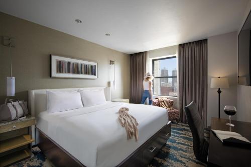 a hotel room with a bed and a woman looking out the window at Hotel Felix in Chicago